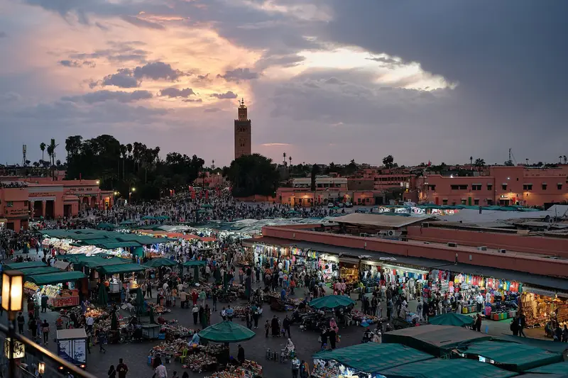 Jemaa el-Fnaa square in Marrakech at dusk, with the Koutoubia minaret in the distance