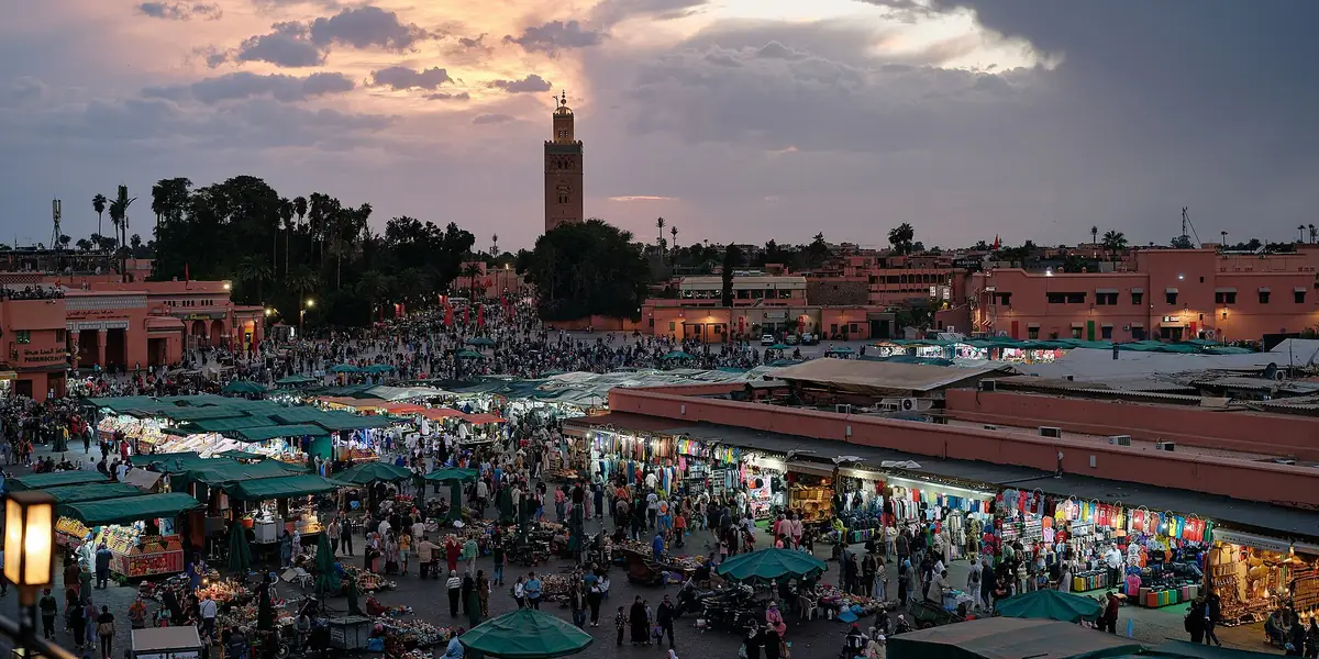 Jemaa el-Fnaa square in Marrakech at dusk, with the Koutoubia minaret in the distance